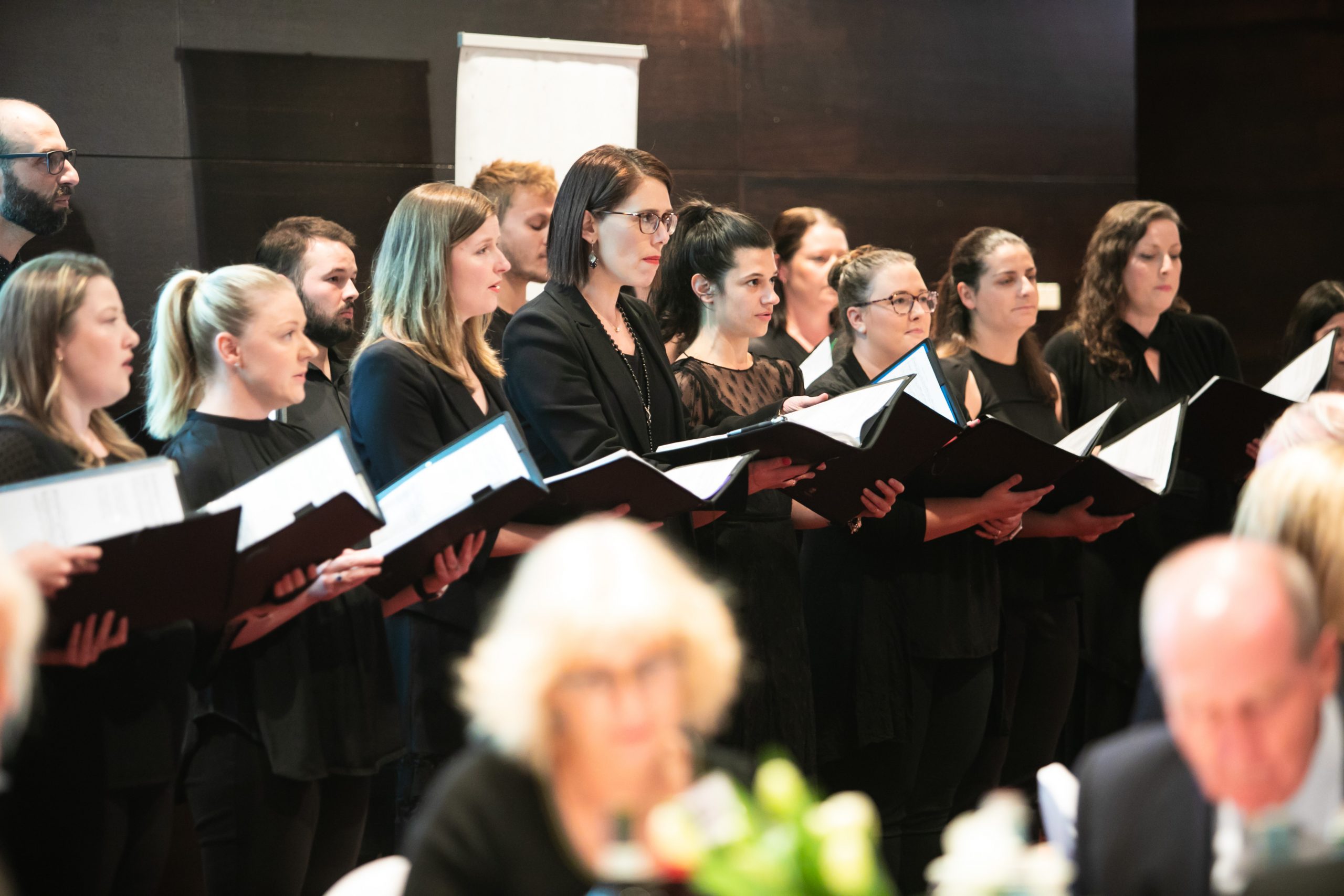 A group of people singing at a banquet.