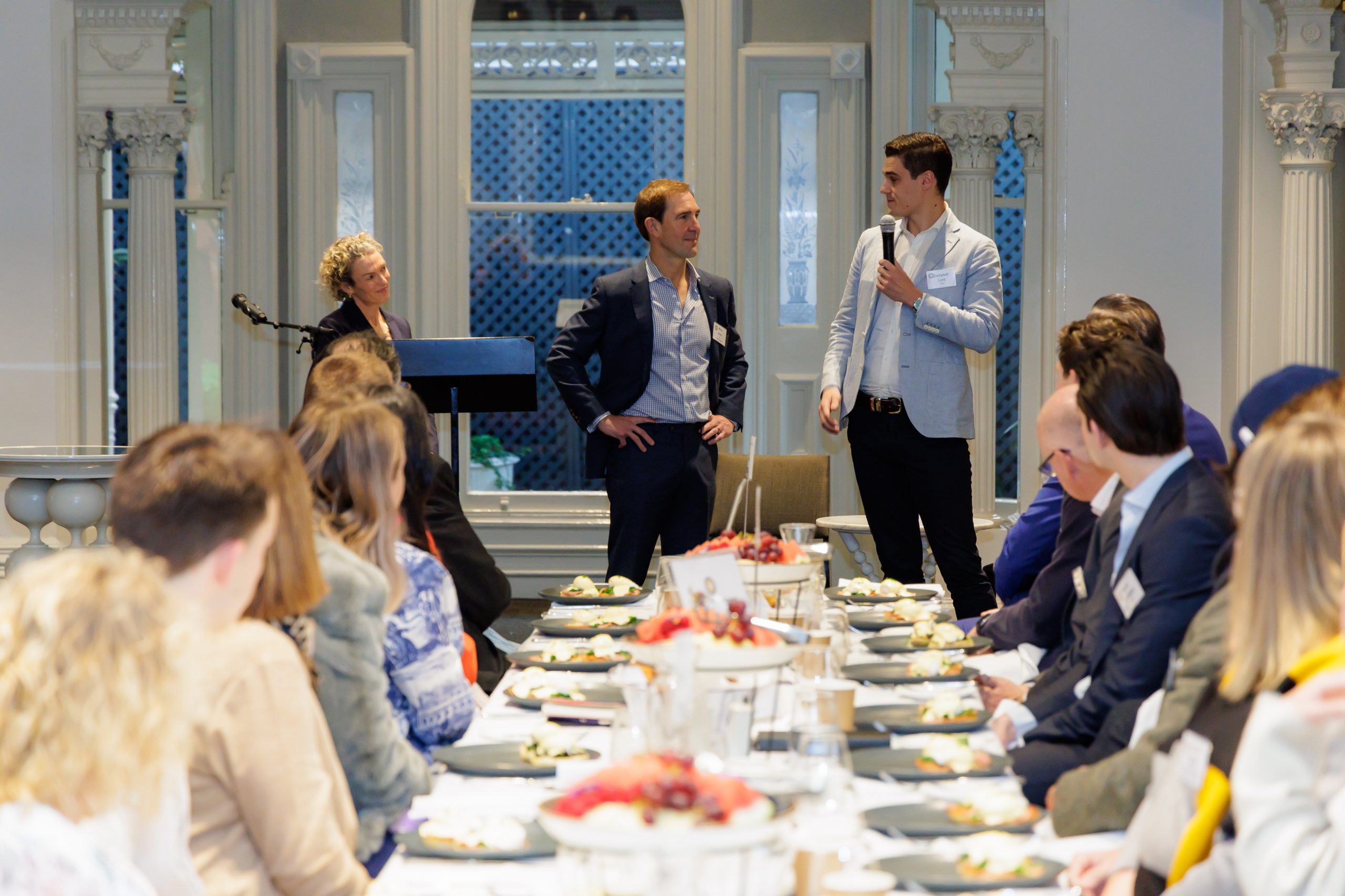 a group of people sitting at a table with plates of food for Reverse Mentoring Breakfast 2023